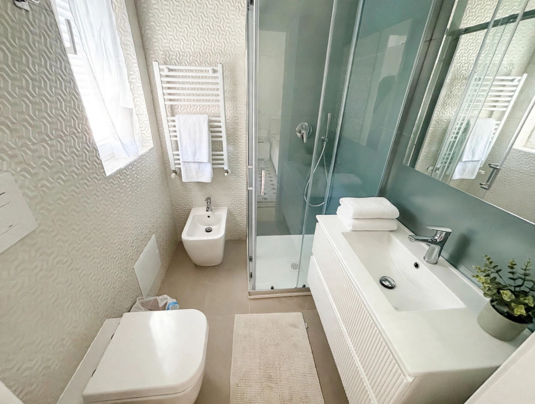 Un bagno moderno con cabina doccia in vetro, lavabo bianco e bidet.