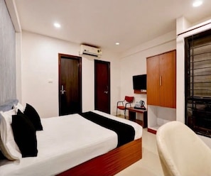 A hotel room with a bed, a desk, a chair, and a wardrobe. - Classic Hotel Expression (Indore)