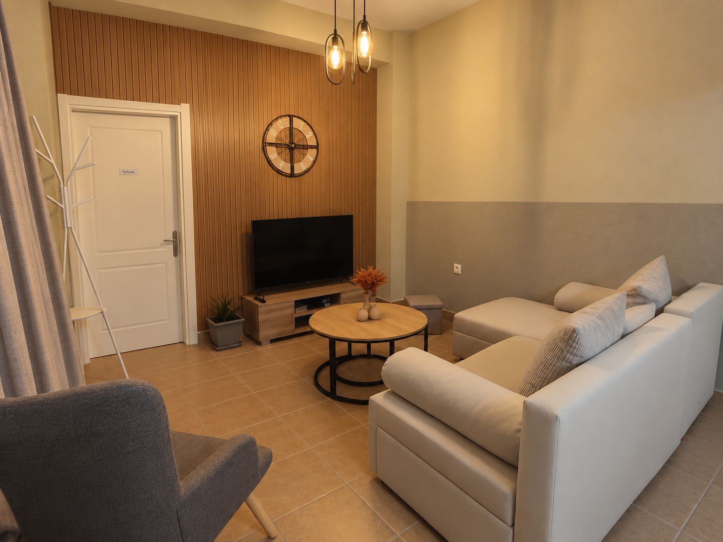 Una sala de estar moderna con un sofá, una mesa de centro, un televisor y un reloj de pared decorativo.