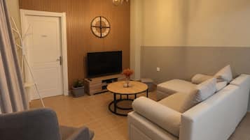 Una sala de estar moderna con un sofá, una mesa de centro, un televisor y un reloj de pared decorativo.
