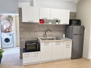 Una cocina compacta con lavadora integrada, microondas y refrigerador.
