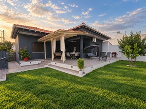 Une maison moderne dotée d’un patio, de mobilier d’extérieur et d’une pelouse bien entretenue.