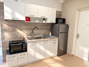 Una cocina compacta con horno integrado, refrigerador, pileta y un botiquín de primeros auxilios sobre la encimera.