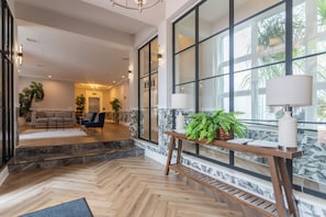 A spacious living area with a herringbone floor, a sofa, a chair, and a coffee table with decorative items. - Historic River District Downtown Escape (Fort Myers)