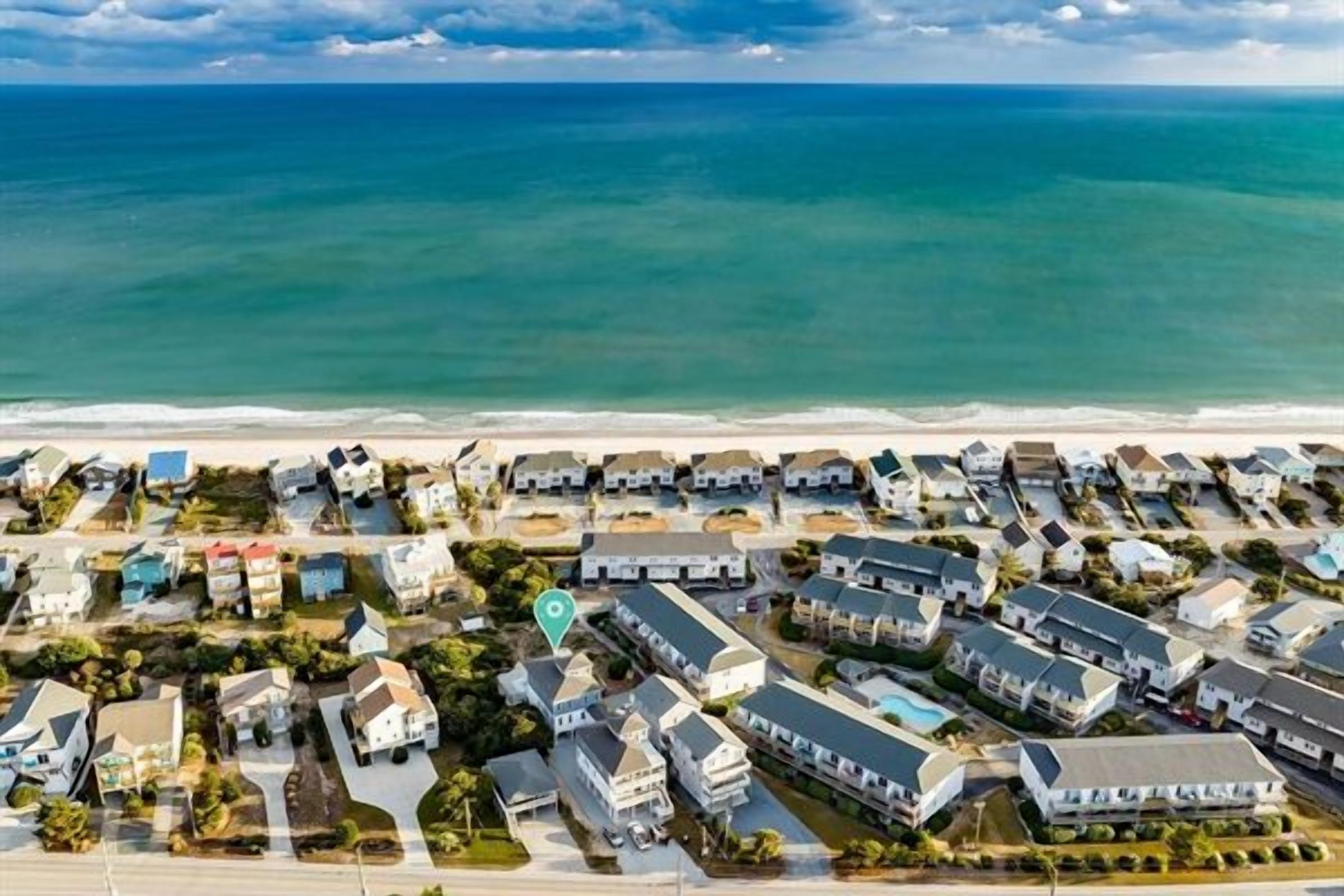 An aerial view of a coastal residential area with houses and a beach.