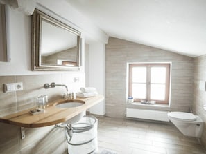 A modern bathroom with a wooden vanity, a large mirror, a window, and a toilet. - Luna Mia Apartment 4 (Schwangau)