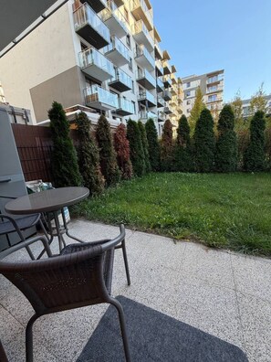 A residential building with multiple balconies and a grassy courtyard with a table and chairs. - Lumina Premium 2BR Apt w/ Parking I AC (Warszawa)