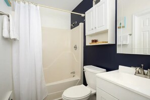 Un bany amb banyera, vàter i un lavabo amb mirall.