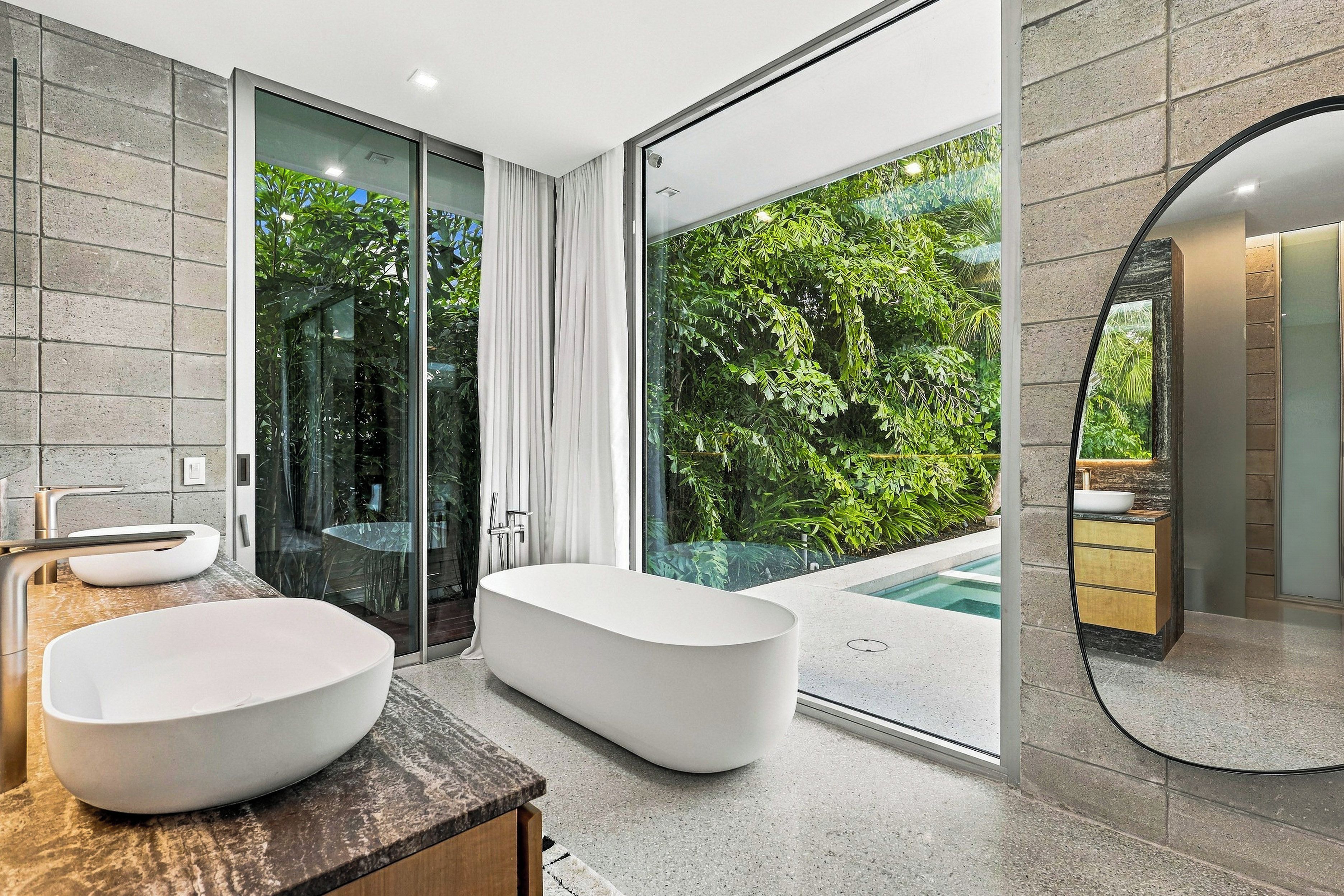 A modern bathroom with a large bathtub, two sinks, and a glass shower enclosure.