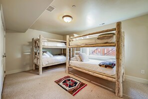Une chambre avec deux lits superposés, une moquette et une fenêtre.