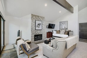 A modern living room with a fireplace, a sofa, a chair, and a television. - Deer Valley Ski Retreat Hot Tub & Fire Pit 1111 2 Bedroom Home (Park City)