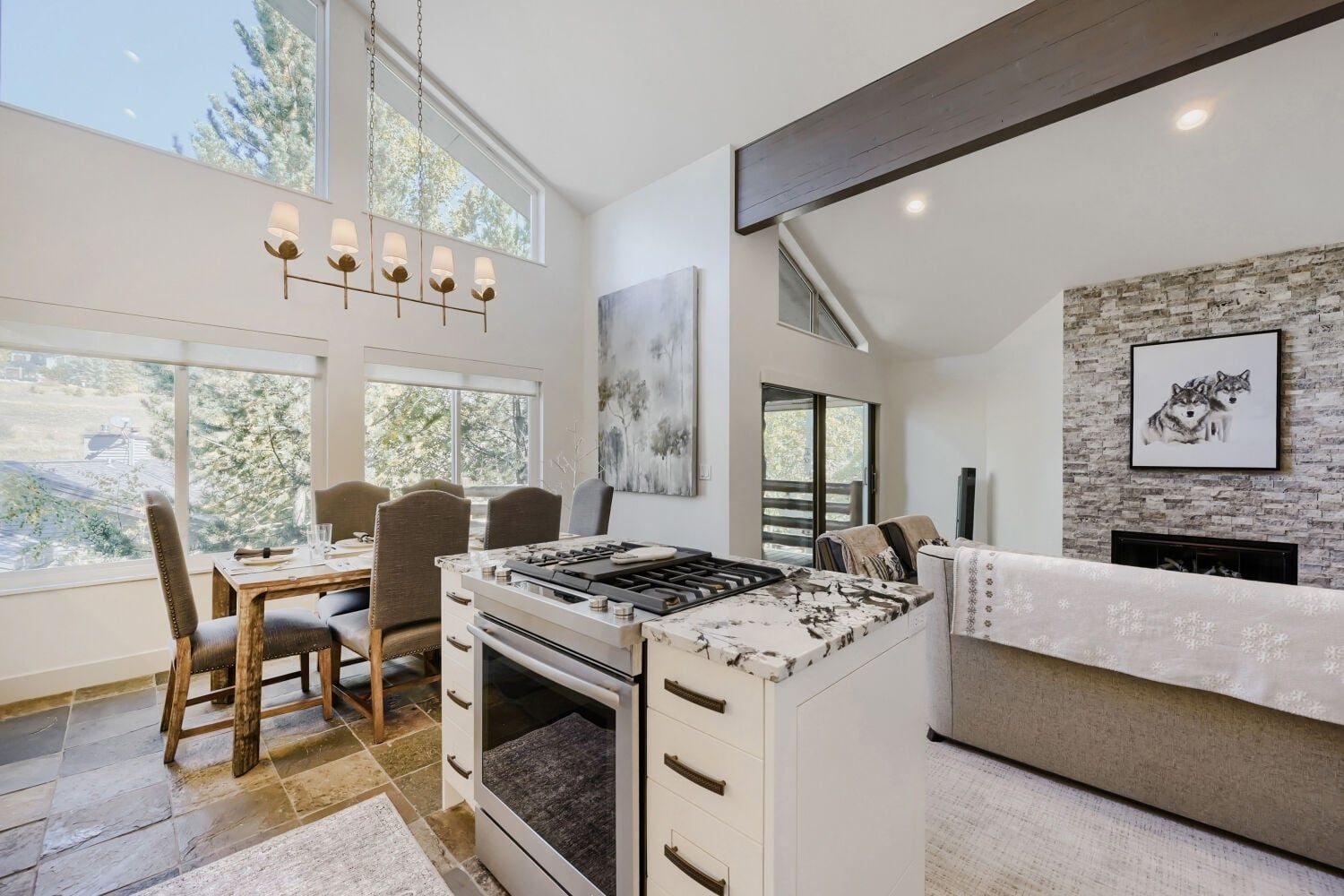 A modern kitchen with a large island, a dining area with chairs, and a fireplace.