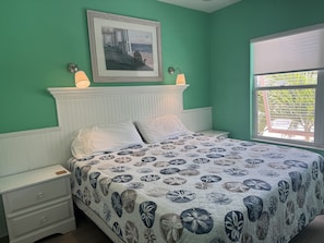 A bedroom with a bed, nightstands, a framed picture, and a window with a view. - Siesta Sunset Royale #12 3 Bedroom Apts (Siesta Key)