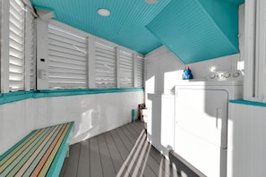 A laundry room with a washing machine, a drying rack, and a bench. - Siesta Sunset Royale #56 3 Bedroom Apts (Siesta Key)