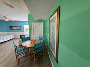 Ein Zimmer mit Esstisch, Stühlen, einem Bett und einem Bild an der Wand.