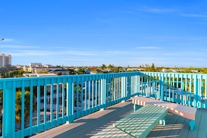 A blue outdoor deck with a bench and a view of a residential area. - Siesta Sunset Royale #5 2 Bedroom Apts (Siesta Key)