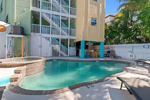 A swimming pool with a hot tub, a covered seating area, and a staircase leading to a multi-level building. - Siesta Sunset Royale #5 2 Bedroom Apts (Siesta Key)
