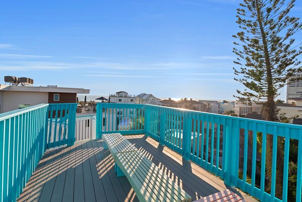 A wooden deck with a turquoise railing, overlooking a residential area with houses and a clear sky. - Siesta Sunset Royale #45 3 Bedroom Apts (Siesta Key)