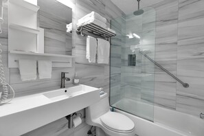 A modern bathroom with a glass shower enclosure, a white sink, and a toilet. - Siesta Sunset Royale #45 3 Bedroom Apts (Siesta Key)