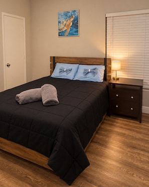 A bedroom with a bed, pillows, a bedside table with a lamp, a door, and a wall with a painting. - Private Pool Retreat - near UCF - Furnished - Long stay welcomed  (Oviedo)