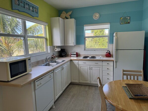 A kitchen with white cabinets, a microwave, a stove, and a refrigerator. - Siesta Sunset Royale #456 4 Bedroom Apts (Siesta Key)