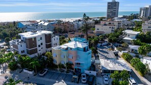 A coastal residential area with multi-story buildings, a parking lot, and a view of the beach and ocean. - Siesta Sunset Royale #123 4 Bedroom Apts (Siesta Key)