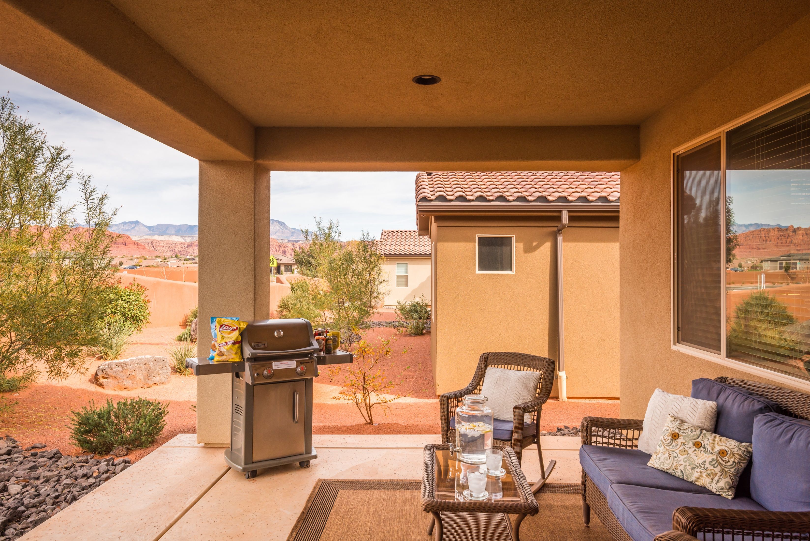 Un patio couvert avec un barbecue, un espace salon et une vue sur le paysage désertique.
