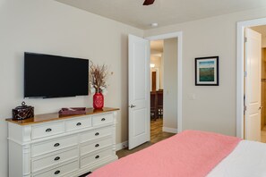 A bedroom with a bed, dresser, television, and a door leading to another room. - Canyonlands #1 3 Bedroom Home (Ivins)