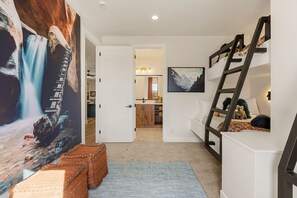 A hallway leading to a bathroom with a wooden cabinet and a painting on the wall. - The Desert Isle 5 Bedroom Townhouse (Washington)