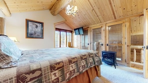 A bedroom with a bed, a television, a heater, and wooden doors. - Sierra Megeve #29 3 Bedroom Condo (Mammoth Lakes)