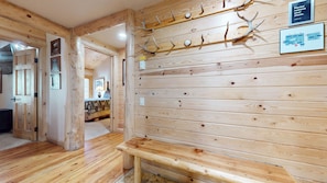Arredamento in legno con una panca, ganci a parete in legno e una targa incorniciata.