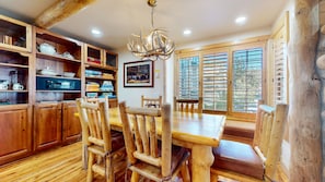 A wooden dining area with a chandelier, wooden chairs, and a table. - Sierra Megeve #29 3 Bedroom Condo (Mammoth Lakes)