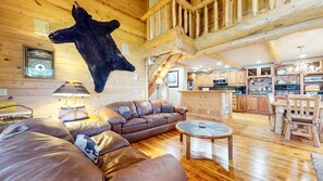A log cabin interior with a leather sofa, a dining table, and a mounted animal hide. - Sierra Megeve #29 3 Bedroom Condo (Mammoth Lakes)