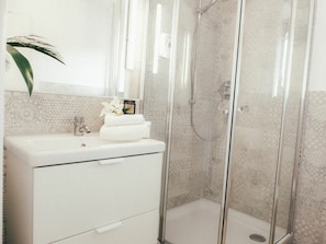 A bathroom with a glass-enclosed shower, a white sink, and a decorative tile backsplash. - House Luna - Apartment Luna 2 (Schwangau)
