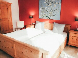 A bedroom with a wooden bed, two bedside tables, a nightstand, a chair, and a wall painting. - House Luna - Apartment Luna 2 (Schwangau)