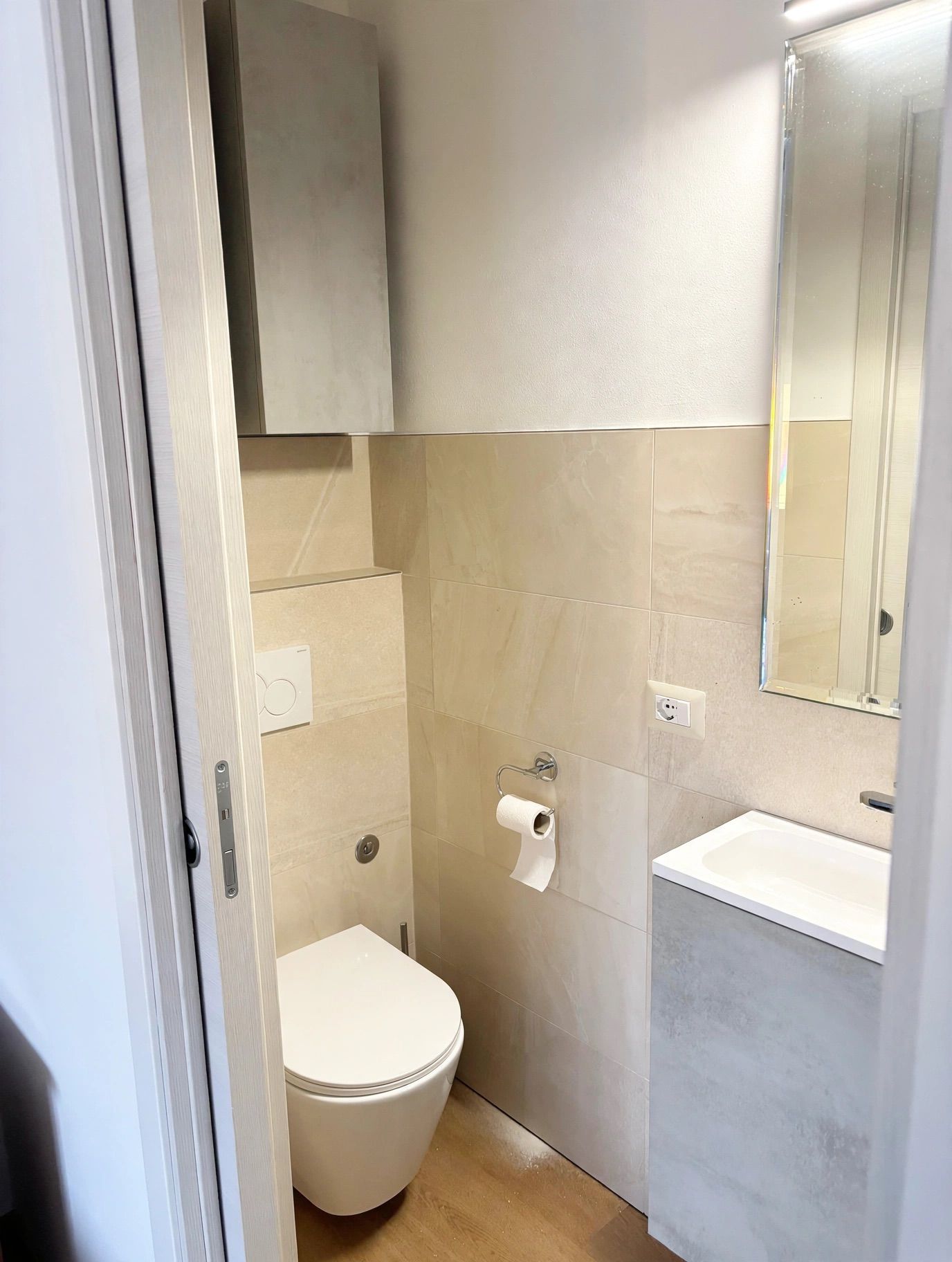 Un bagno moderno e piccolo con il water, un lavandino e uno specchio.