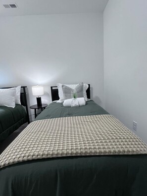 A hotel room with two beds, a bedside table with a lamp, and a wall-mounted air vent. - The Best Place for Family Stays, and Small Group (Mint Hill)