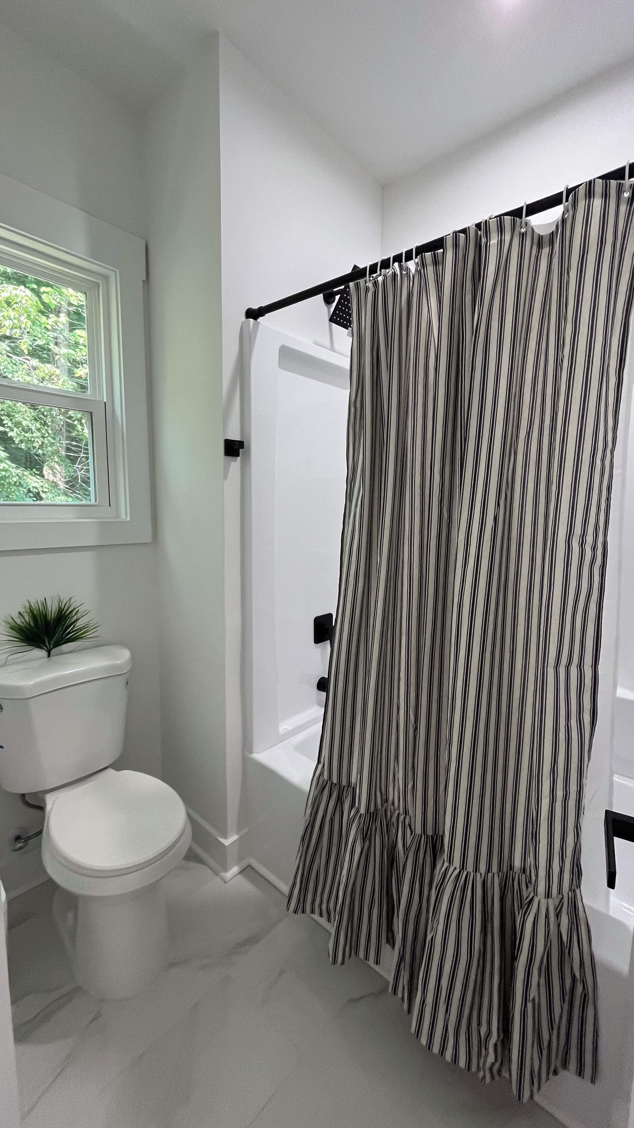 Une salle de bain équipée de toilettes, d’un lavabo, d’une baignoire et d’un rideau de douche.