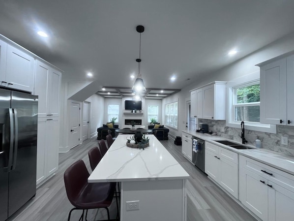A modern kitchen with white cabinetry, a central island, and a dining area with chairs.