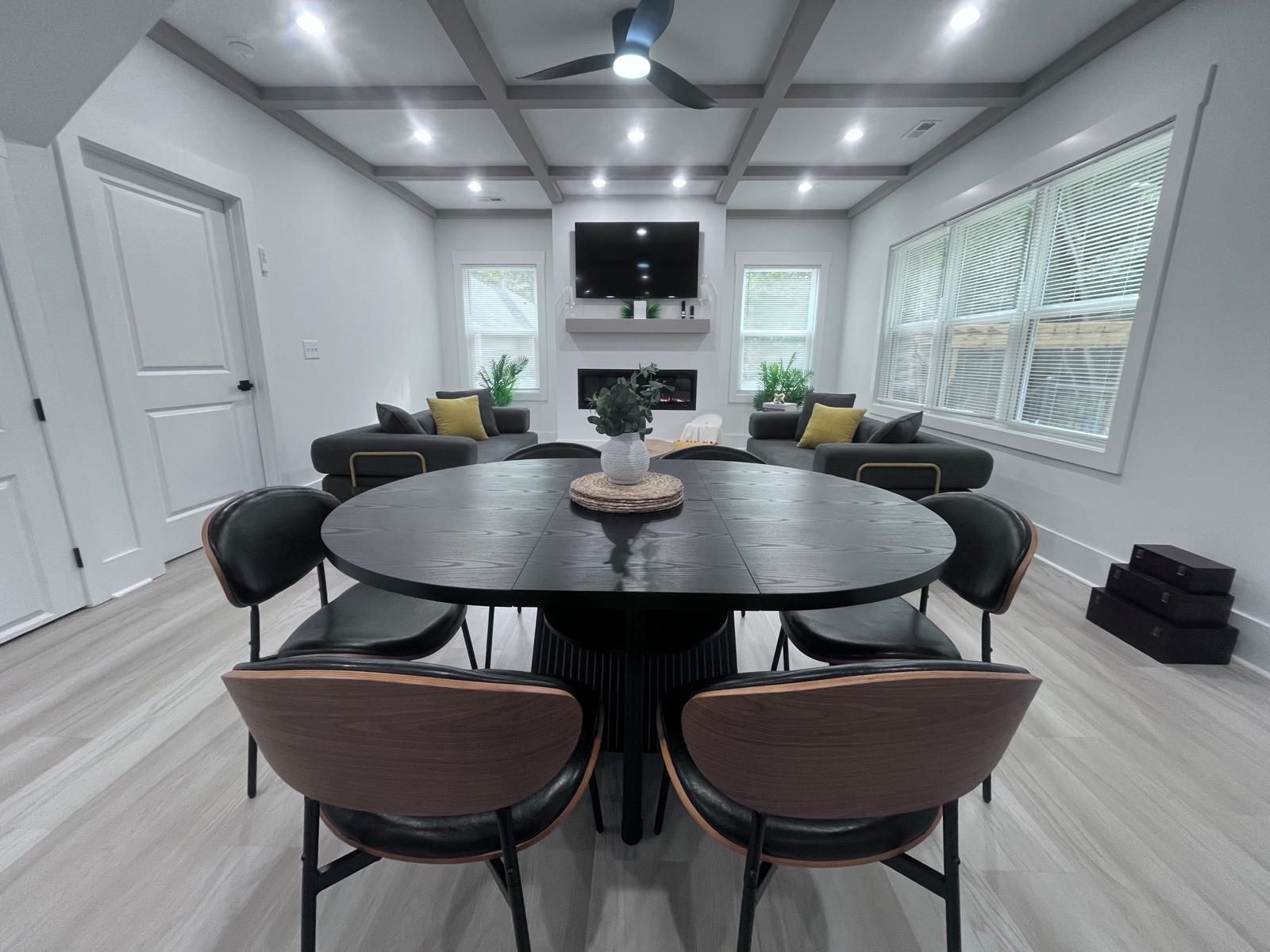 Une salle de réunion moderne avec une table ronde, des chaises noires et un ventilateur de plafond.