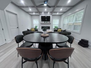A modern meeting room with a round table, black chairs, and a ceiling fan.