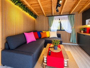 Un interno moderno con un divano componibile, un soffitto in legno e una zona cucina.