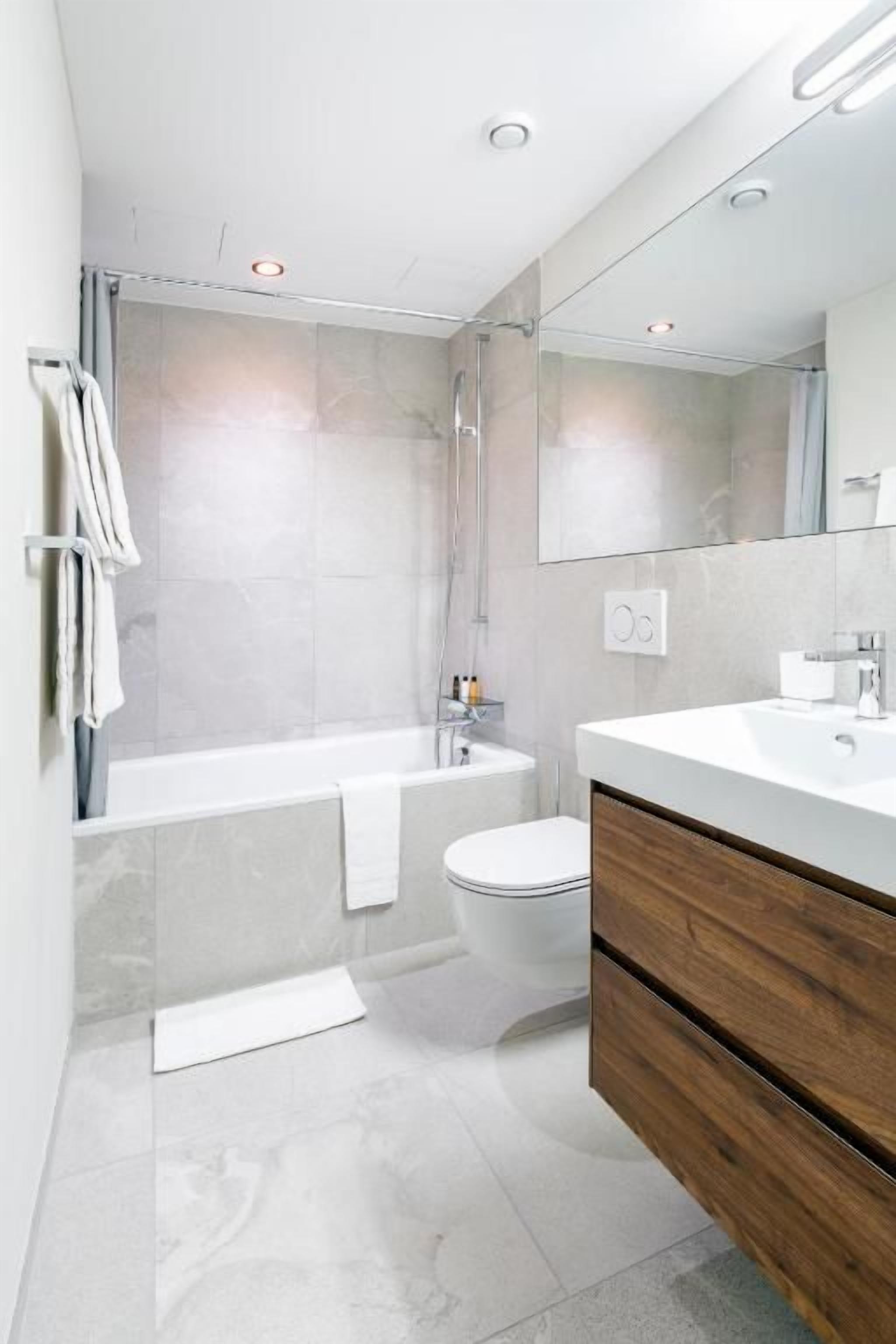 A modern bathroom with a bathtub, toilet, and vanity.