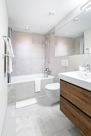 Un baño moderno con bañera, inodoro y tocador.