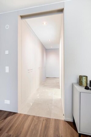 A hallway with a wooden floor, a white cabinet, and a door leading to another room. - CITY STAY - Papieri-Ring (Cham)