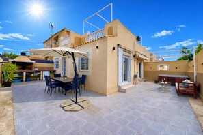 Eine Terrasse mit Tisch und Stühlen, einem Grill und einem Whirlpool.