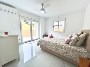 Ein Schlafzimmer mit Bett, Schreibtisch, Deckenventilator und Fenster.