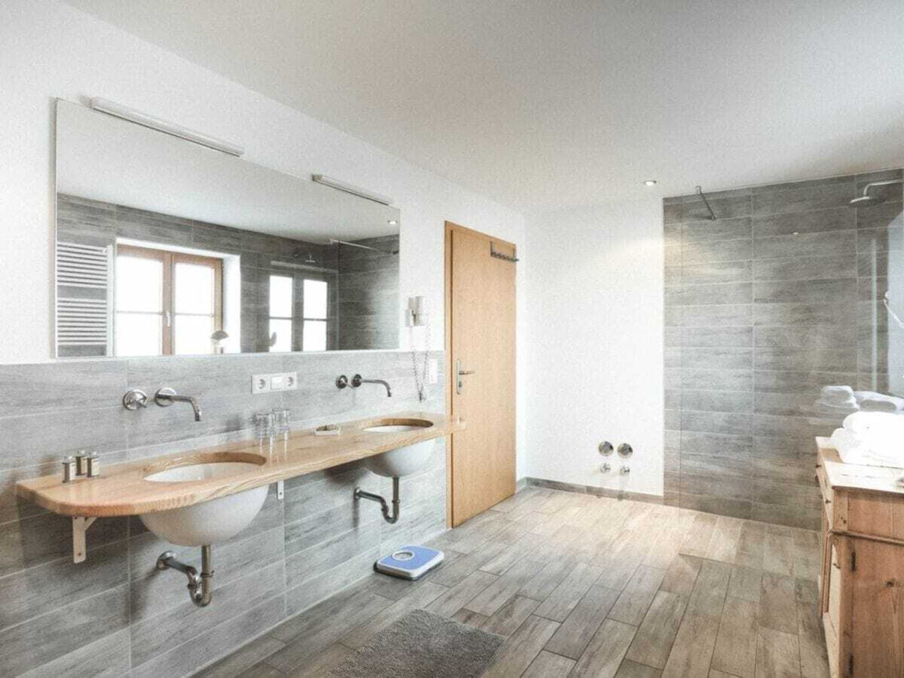 Ein modernes Badezimmer mit zwei Waschbecken, einem großen Spiegel und einer Duschkabine.