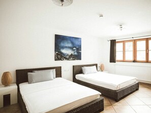 A hotel room with two beds, a large window with curtains, a wall-mounted picture, and a ceiling light fixture. - Luna Mia Apartment 3 (Schwangau)