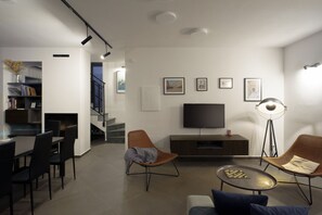 A modern living room with a flat-screen TV, two wicker chairs, a coffee table, and a bookshelf. - New Listing (Krnica)